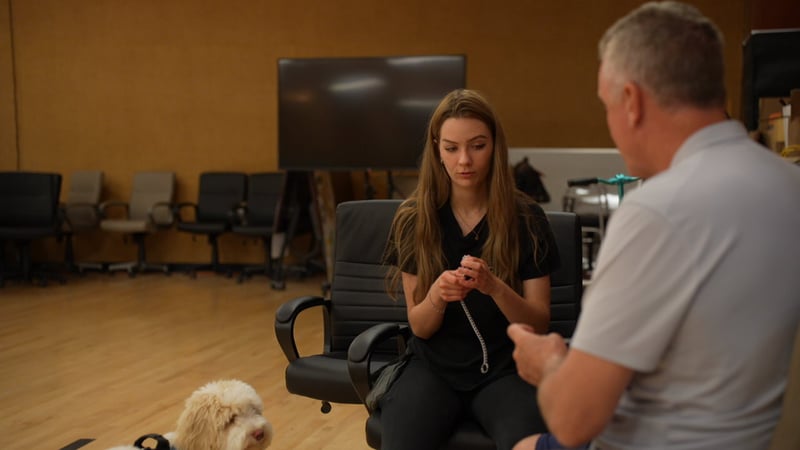 Partners Dogs trainer coaching a client one-on-one while her doodle rests nearby