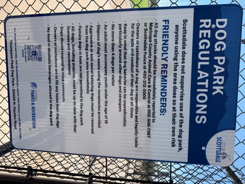 The posted Dog Park Regulations sign at Thompson Peak Dog Park in Scottsdale, listing the four-dog limit, voice-command rule, and attack-reporting numbers.